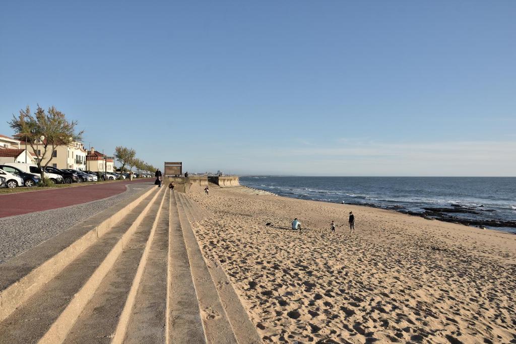 a beach with people walking on the sand and the ocean at Retiro da Praia da Aguda in Arcozelo
