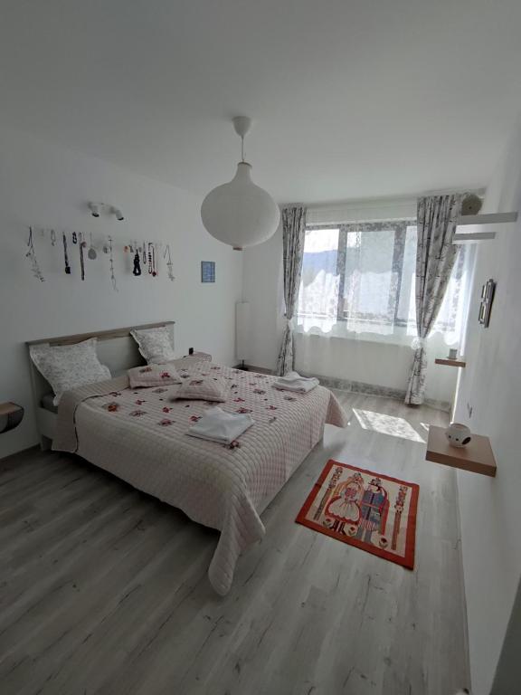 a white bedroom with a large bed and a wooden floor at Happy Home in Călimăneşti
