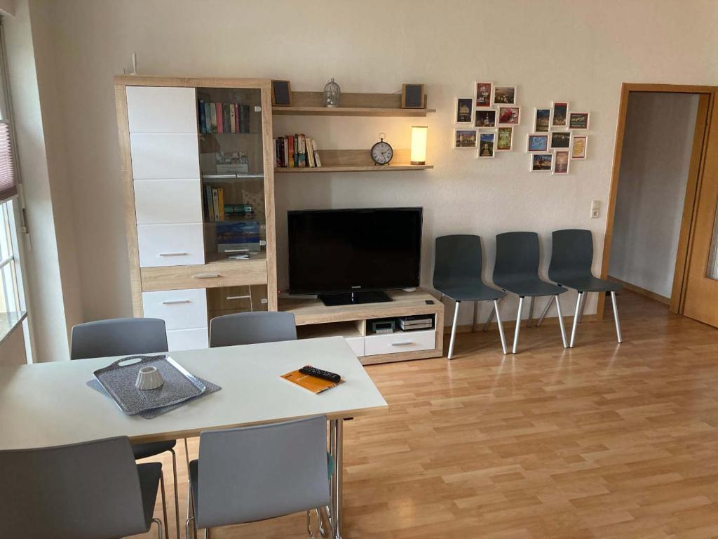 een woonkamer met een tafel en stoelen en een televisie bij Ferienwohnung Tapetenwechsel -Balkon- in Dresden