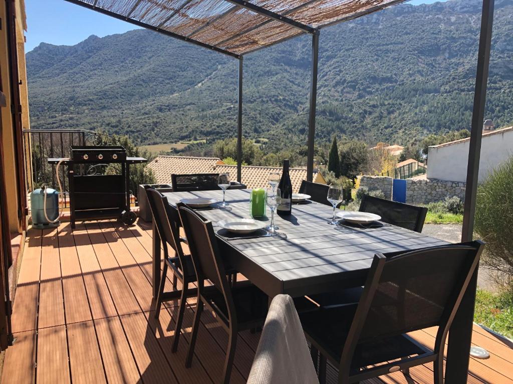 a table on a deck with a view of a mountain at Gîte San Jordi in Duilhac