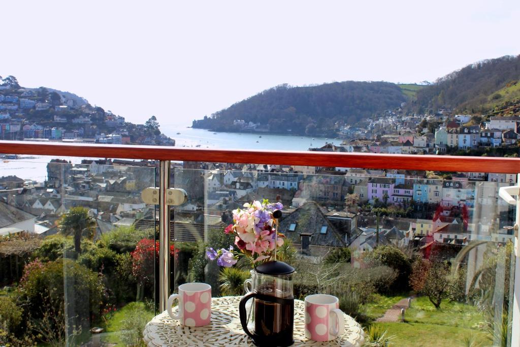 a table with a coffee pot and flowers on a balcony at The Lookout at Lauriston in Dartmouth