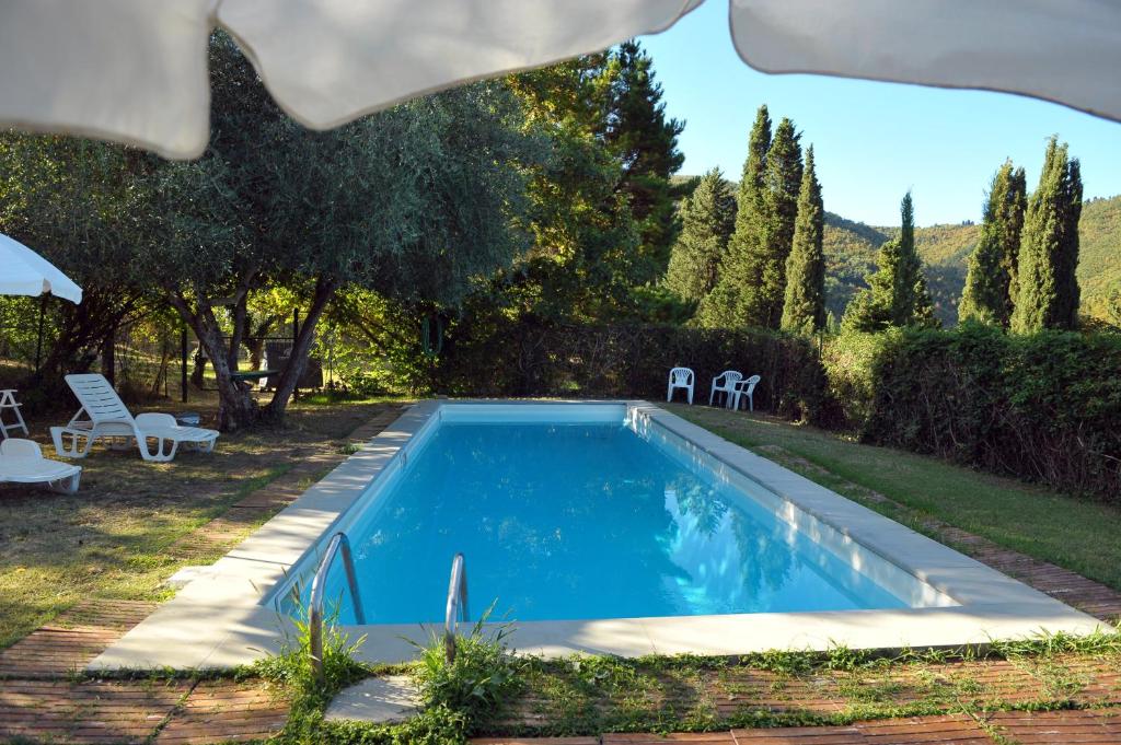 una piscina en un patio con sillas y árboles en La Villa di Caiano, en Londa