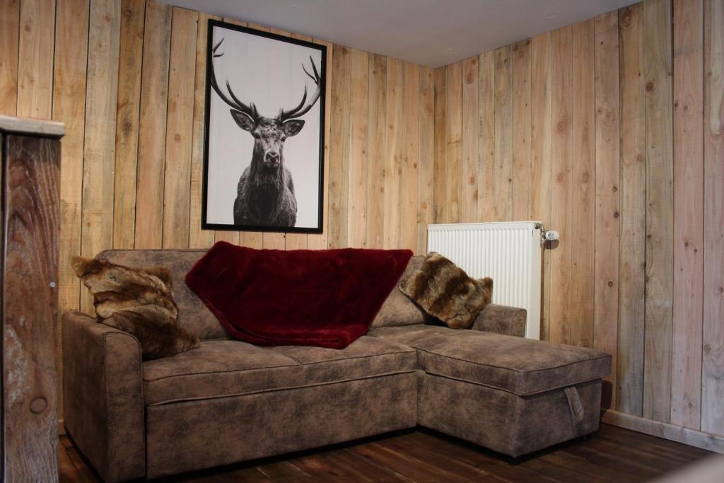 una sala de estar con sofá y una foto de ciervo en Cabane chez Manu en Durbuy