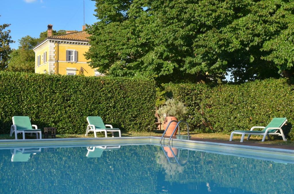 una piscina con 2 sillas y una casa en Palazzo Di Bagnaia, en Castel del Piano