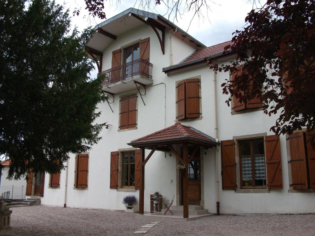 una grande casa bianca con finestre in legno e una porta di Chambre Hôte Villa Sainte Barbe a Mirecourt