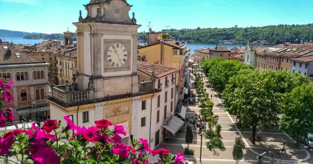 una torre del reloj en la parte superior de un edificio con flores rosas en Hotel Eden Salò, en Saló