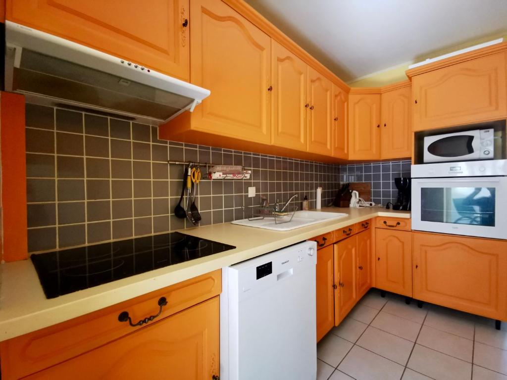 a kitchen with wooden cabinets and a sink and a microwave at COC - La Belle Etoile in Wissant