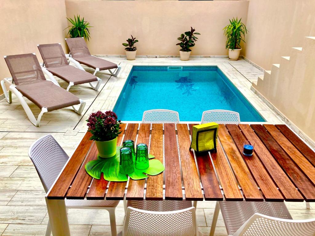 Casa Mediterránea con piscina privada en Palamós في بالاموس: طاولة وكراسي خشبية بجانب مسبح