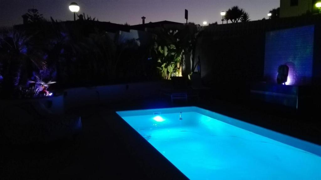 una piscina por la noche con luces azules en Petit Paradis en Manilva