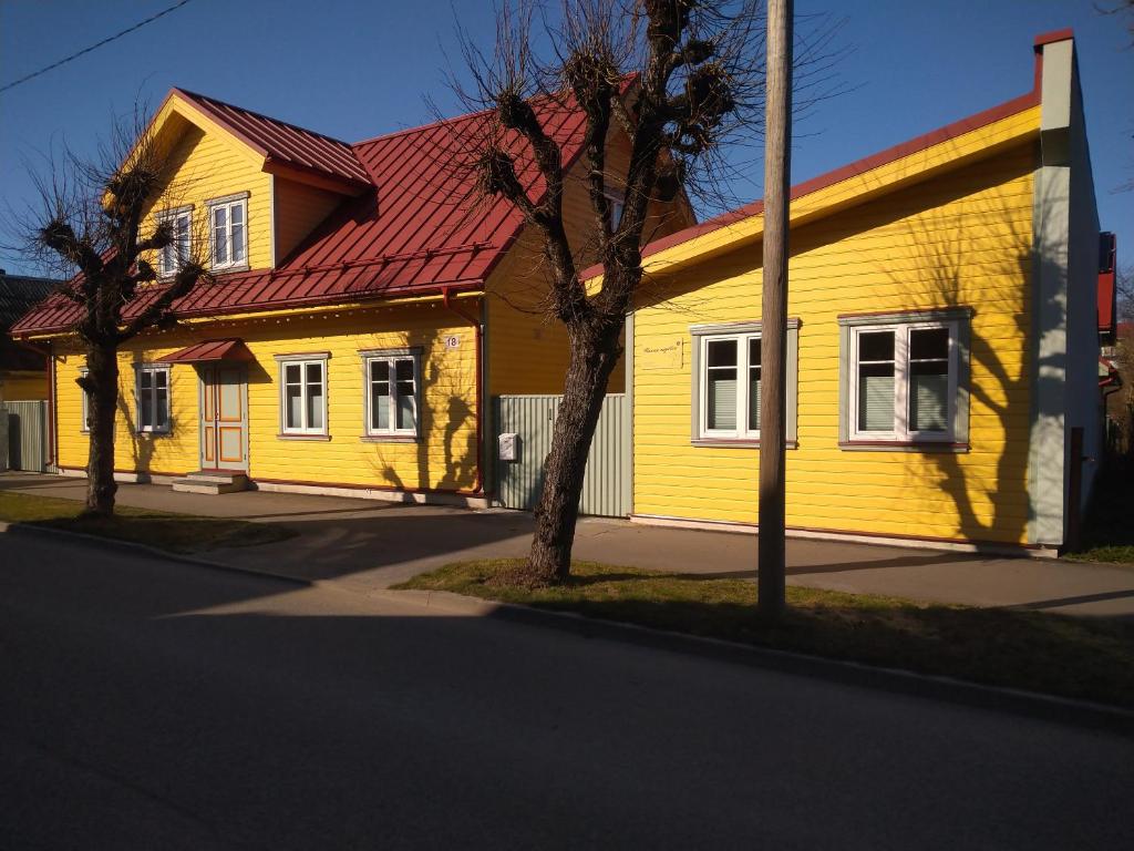 uma casa amarela com um telhado vermelho numa rua em Ranna majutus em Pärnu