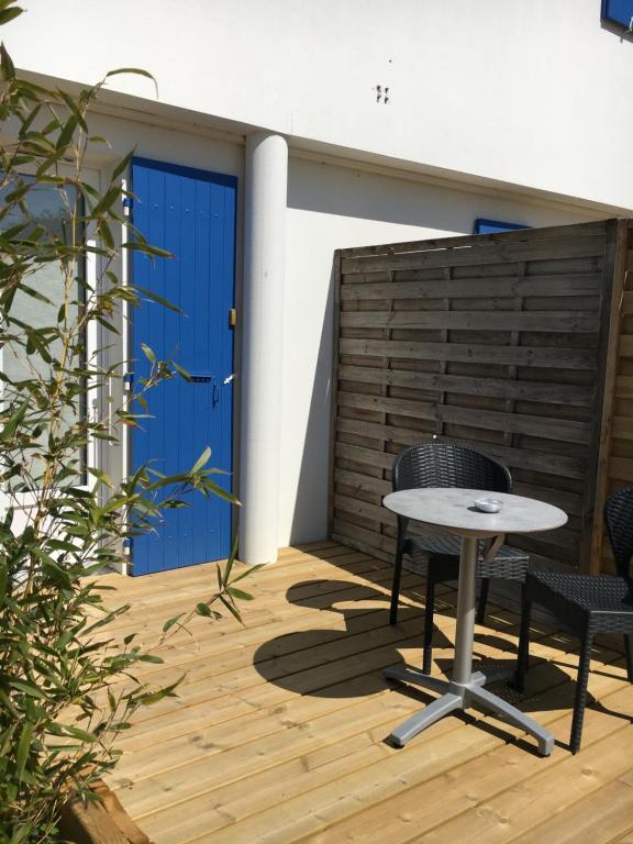 a patio with a table and chairs on a wooden deck at Les Bains Boyardville - Hôtel et Restaurant in Boyard-Ville