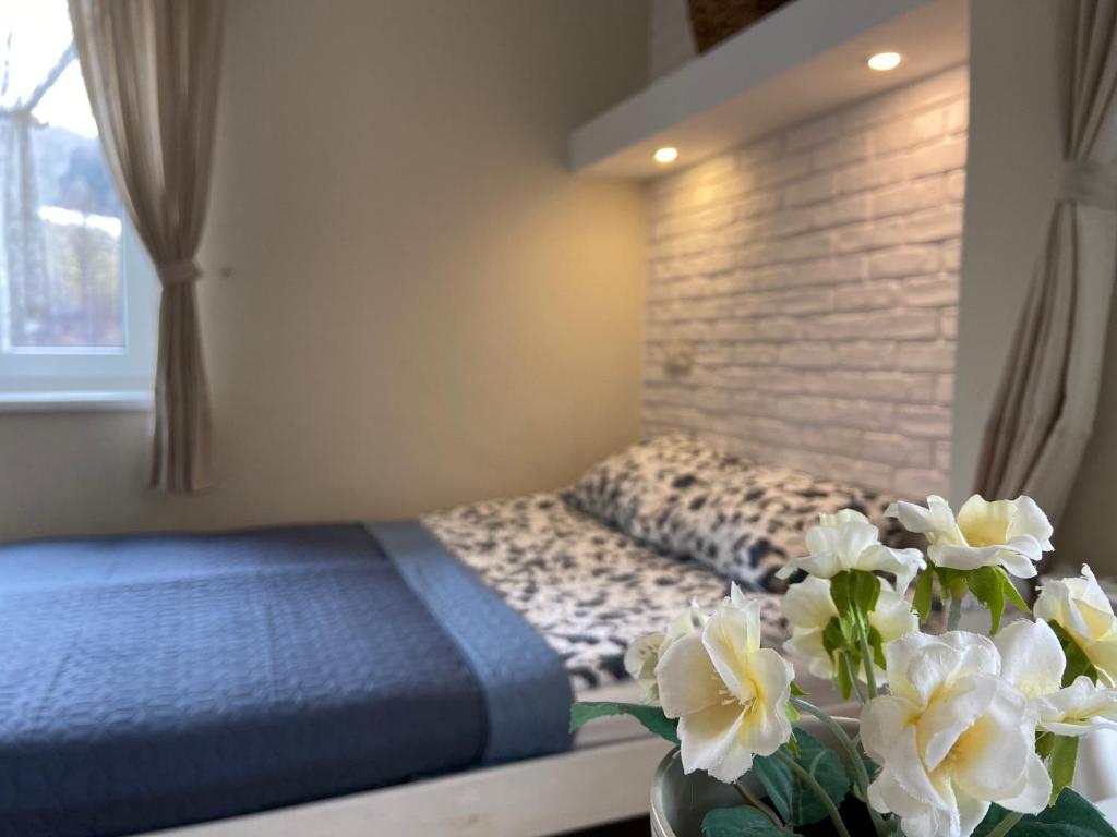 a bedroom with a bed and a vase of flowers at Willa Aleksandra - Apartamenty in Międzybrodzie Żywieckie