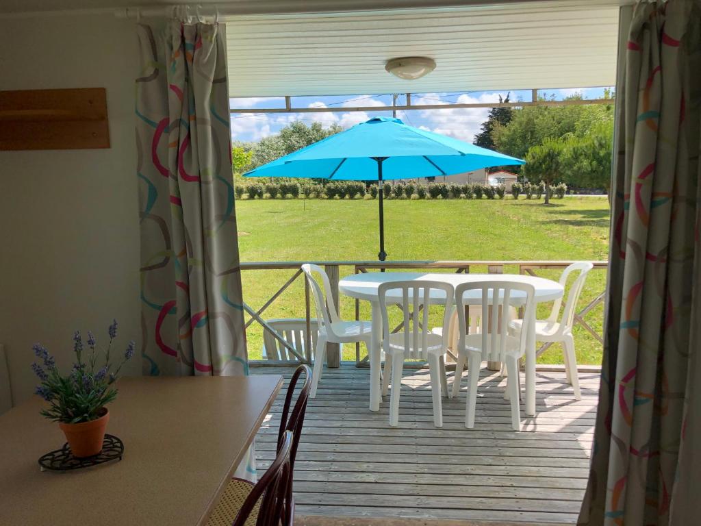 einen Tisch und Stühle mit einem Sonnenschirm auf einer Terrasse in der Unterkunft LE MEDOC AUX 4 VENTS in Jau-Dignac-et-Loirac