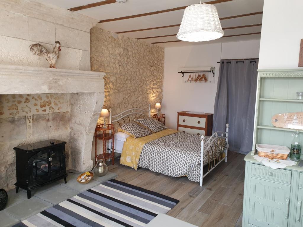 a bedroom with a bed next to a fireplace at La Vieille Grange - NOUVEAU - in Saint-Privat-des-Prés