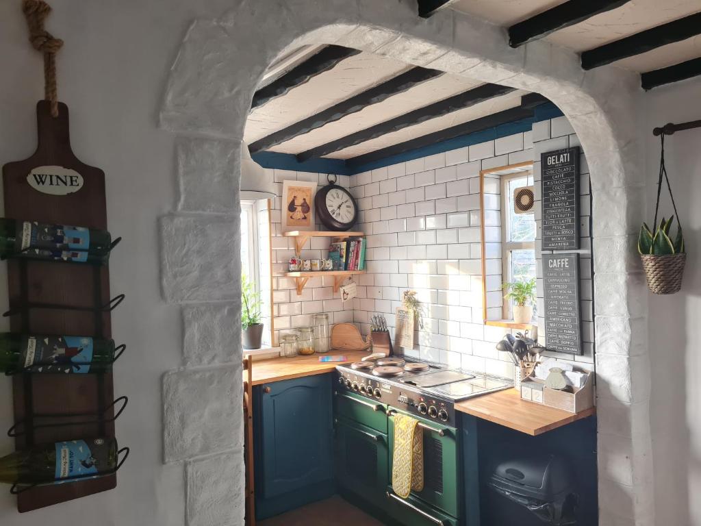une cuisine avec une cuisinière bleue et une voûte dans l'établissement Old Road Cottage Pet Friendly Outdoors Beaches, à Neath