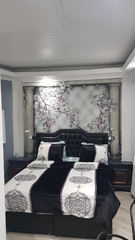 a bedroom with two beds and a wall with flowers at Le petit Luxembourg in Montignies-sur-Sambre
