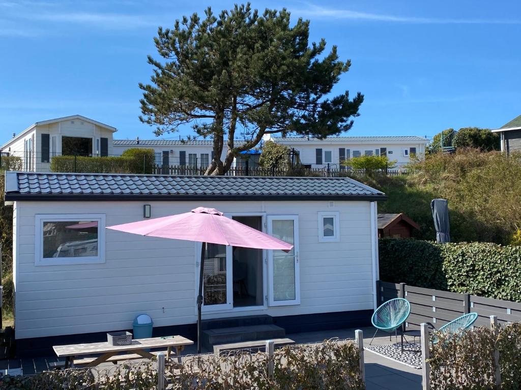 een roze paraplu voor een klein huisje bij Luxe Chalet Marbella IJmuiden aan Zee in IJmuiden