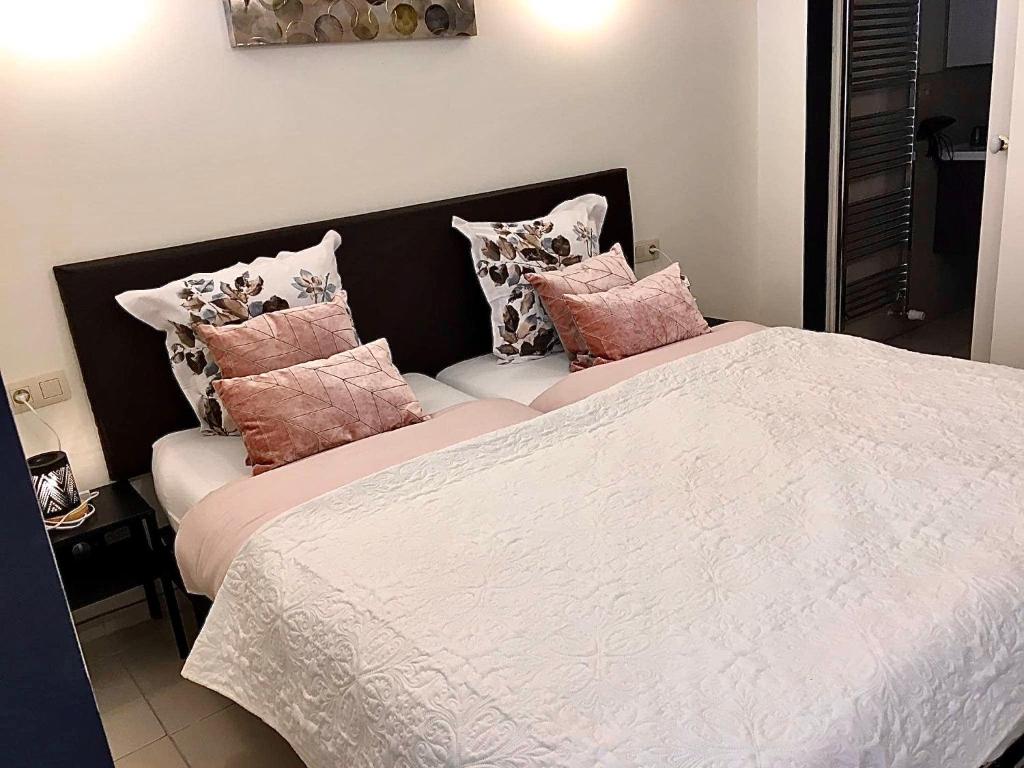 1 dormitorio con 1 cama con almohadas rosas y blancas en Nocturno, en La-Roche-en-Ardenne