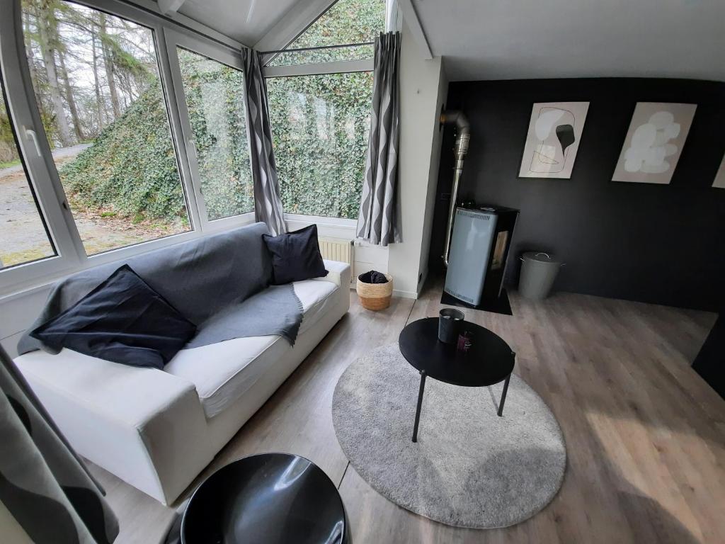 uma sala de estar com um sofá branco e uma mesa em La pinède - Charmante maison de village em Hotton