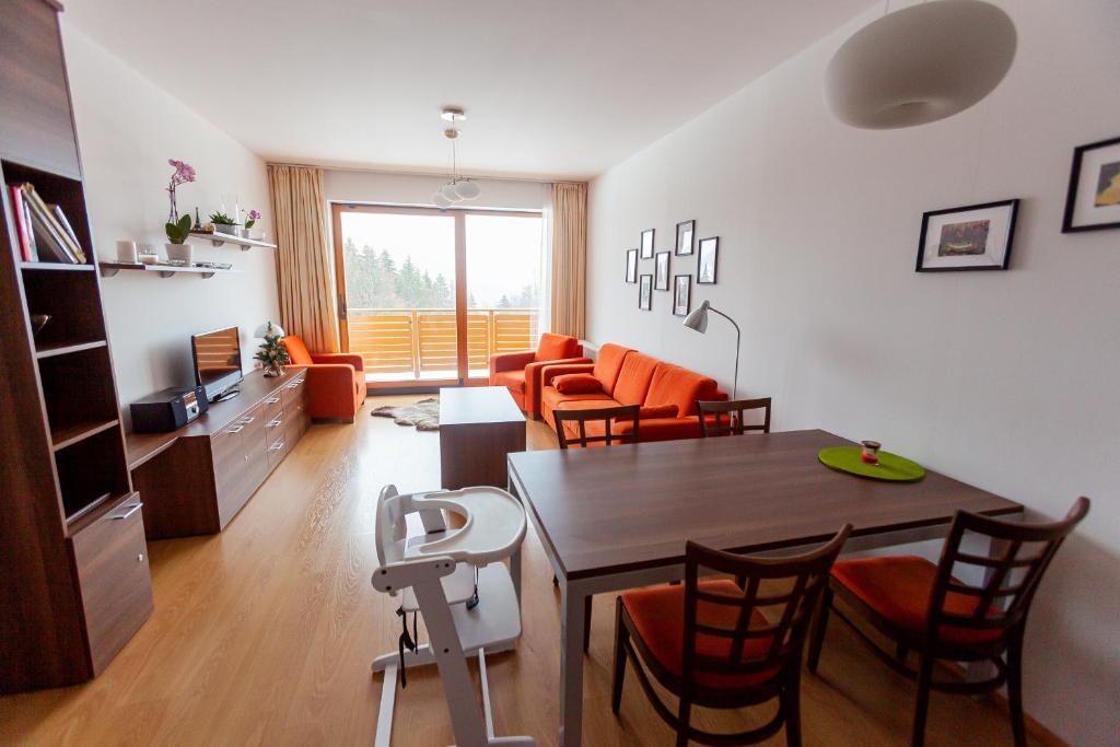 a dining room and living room with a table and chairs at Ski IN-OUT Apartmán Donovaly in Donovaly