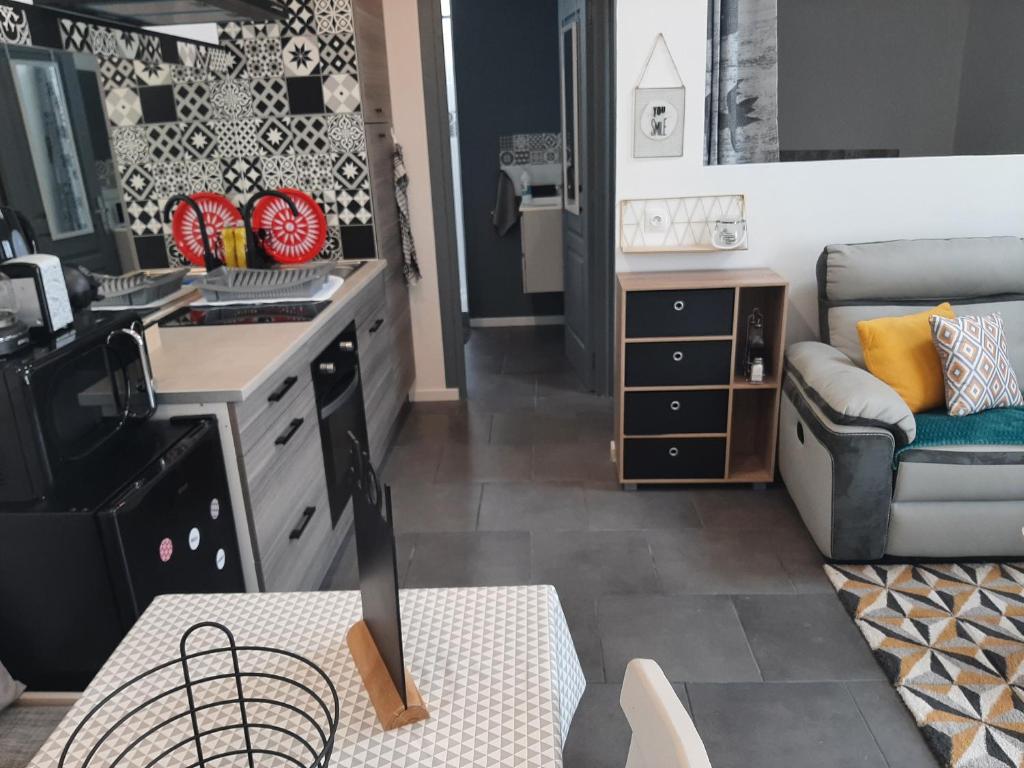cocina y sala de estar con sofá y mesa en petite maison sympathique plein de charme, en Beychac-et-Caillau
