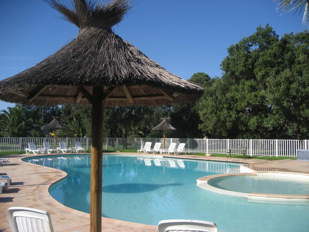 - une piscine avec un parasol et des chaises en paille dans l'établissement Liflosa, à Lecci