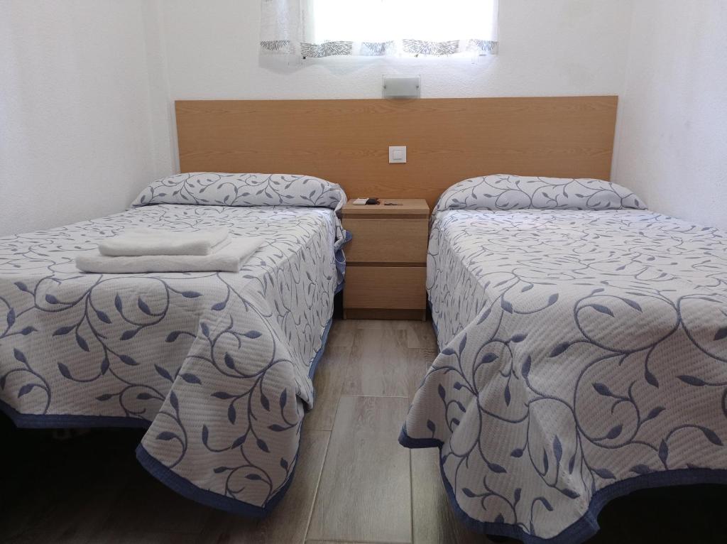 een slaapkamer met 2 bedden en een raam bij Pension Cuatro Torres in Madrid
