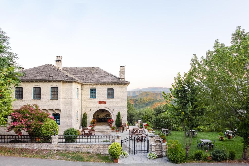 a large white house with a yard with tables and chairs at Beloi Hotel in Vitsa