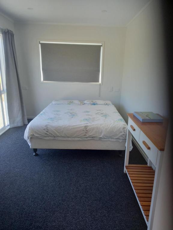 a small bedroom with a bed and a desk at North Hideaway in Pukenui