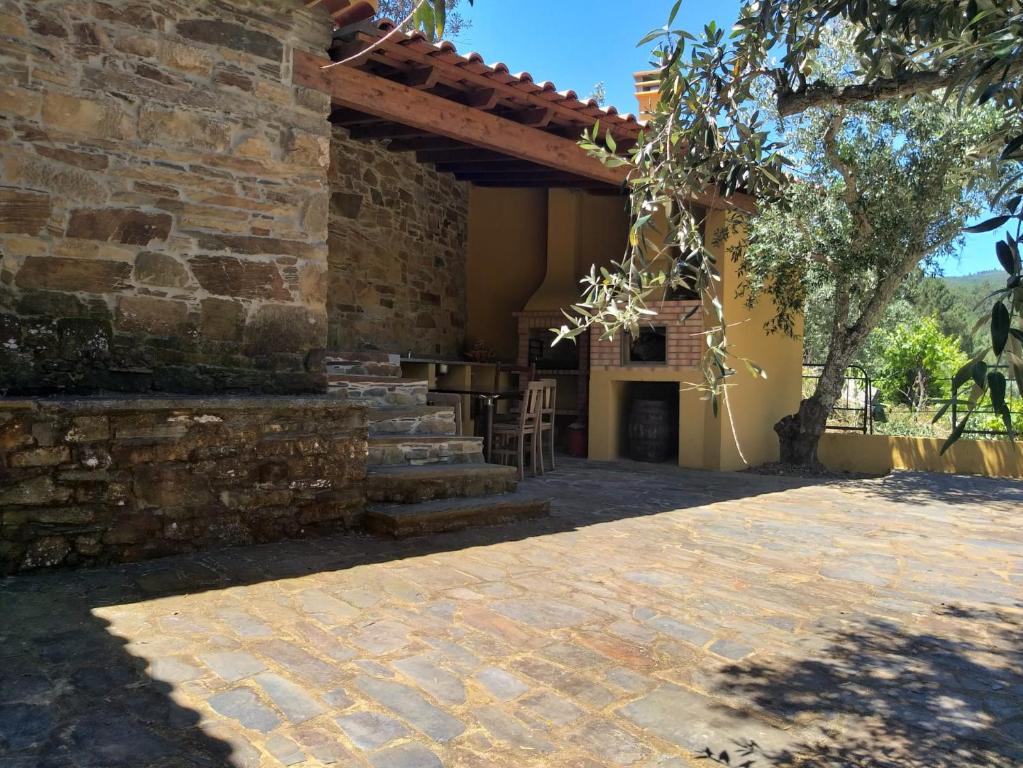 an outdoor patio with a stone wall and a wooden pergola at Casas da Cabrieira in Proença-a-Nova