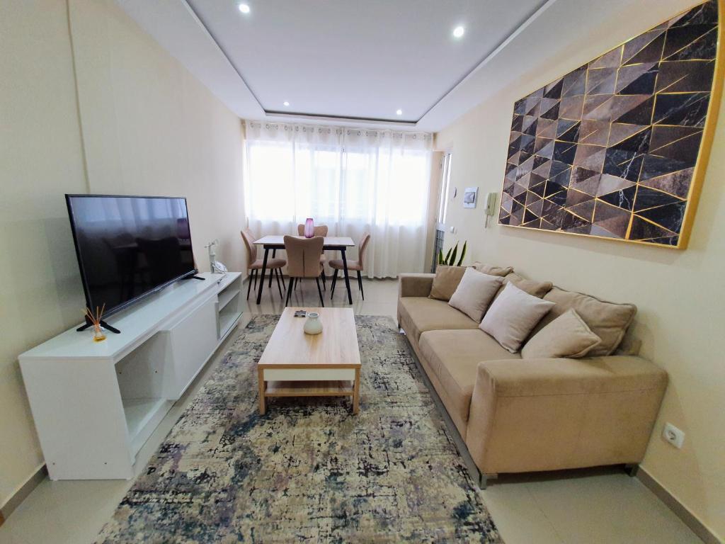 a living room with a couch and a tv and a table at kelly's House Plateau City Center in Praia