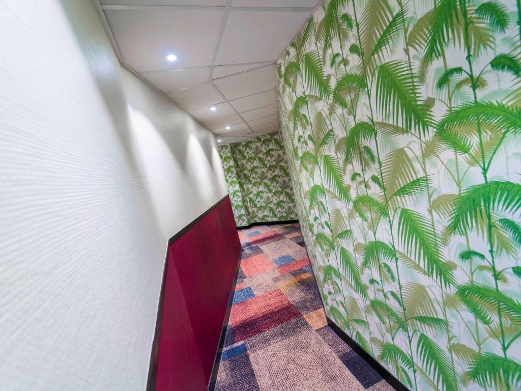 a hallway with a mural of palm trees on the wall at ibis Styles Paris Boulogne Marcel Sembat in Boulogne-Billancourt