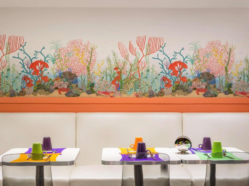 two tables in a restaurant with a flower mural on the wall at ibis Styles Paris Boulogne Marcel Sembat in Boulogne-Billancourt