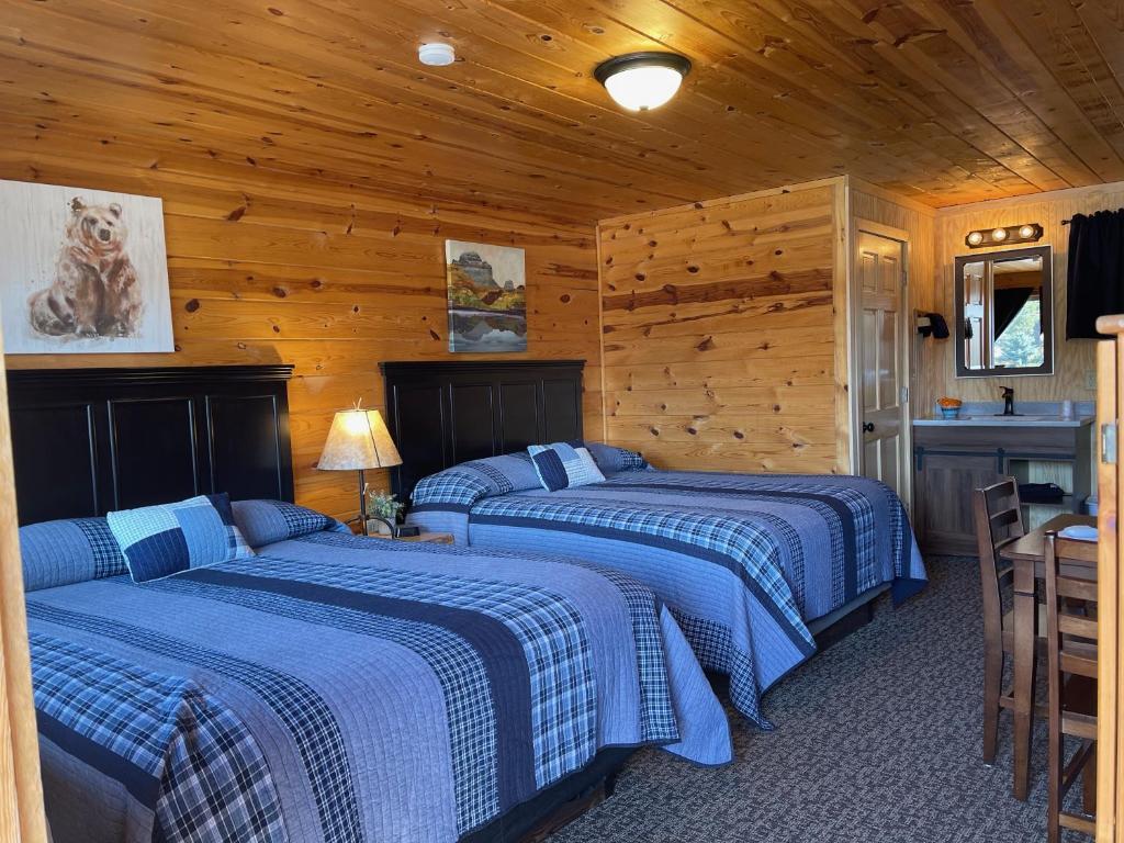 two beds in a room with wooden walls at Mountain View Lodge & Cabins in Hill City
