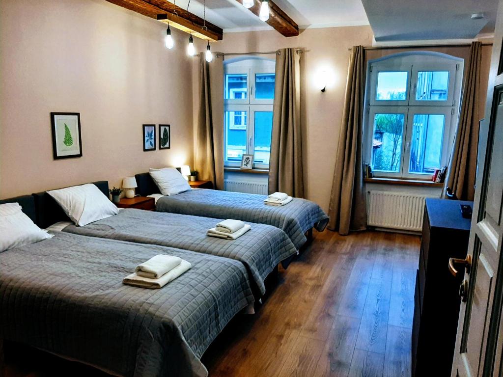 Habitación con 2 camas y ventana en Drzewna Apartamenty - Kupiecka, en Zielona Góra
