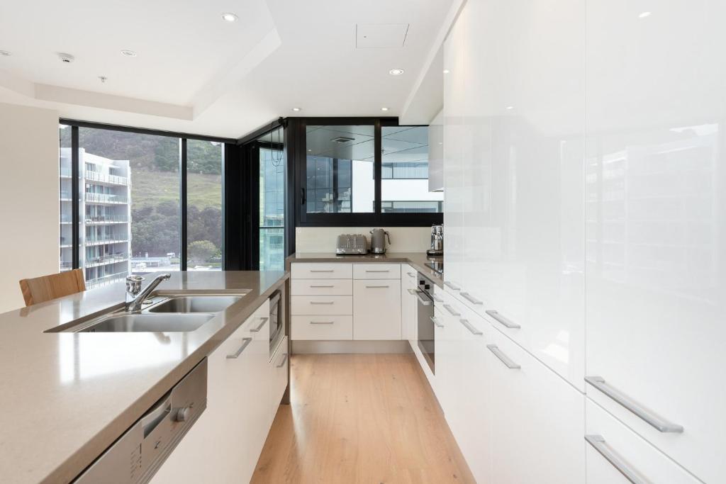 uma cozinha com armários brancos e uma grande janela em Superb Elevated Views of Harbour with Heated Pool, Gym & Parking em Mount Maunganui