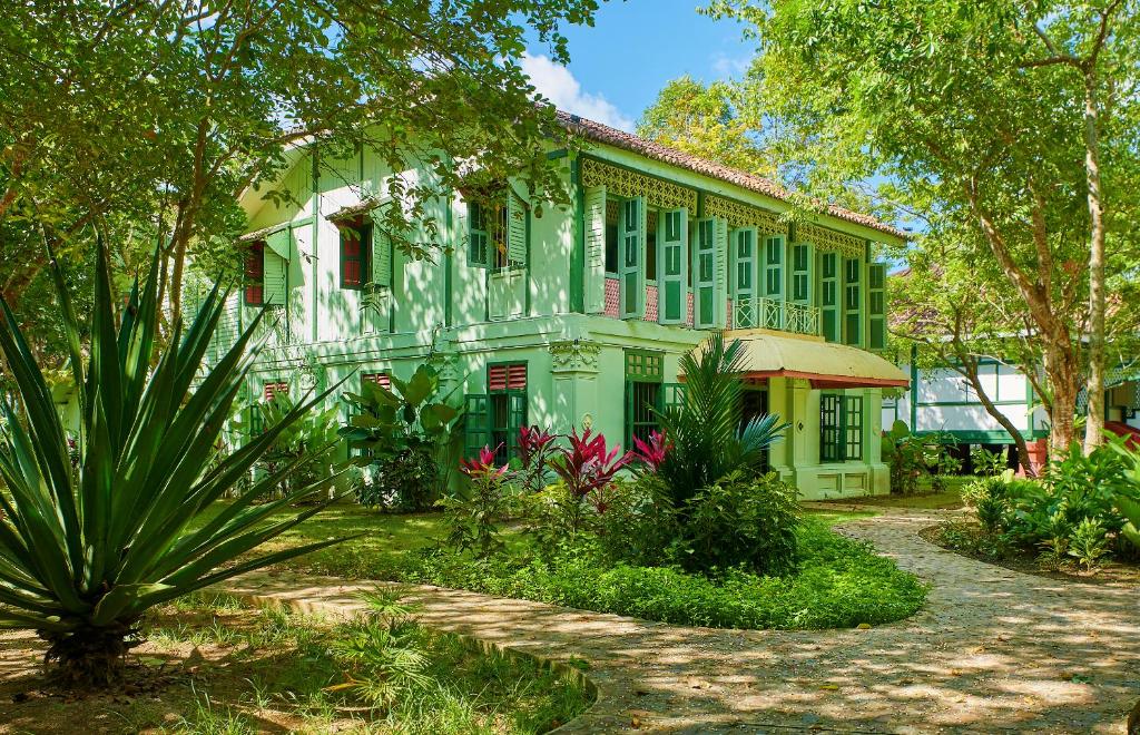 ein grünes Gebäude mit Bäumen und Pflanzen davor in der Unterkunft Temple Tree Resort in Pantai Cenang