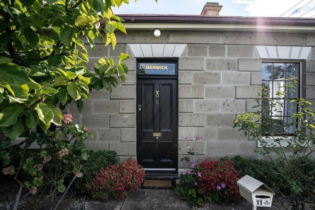 a house with a black door with a sign on it at Berwick Cottage in Hobart