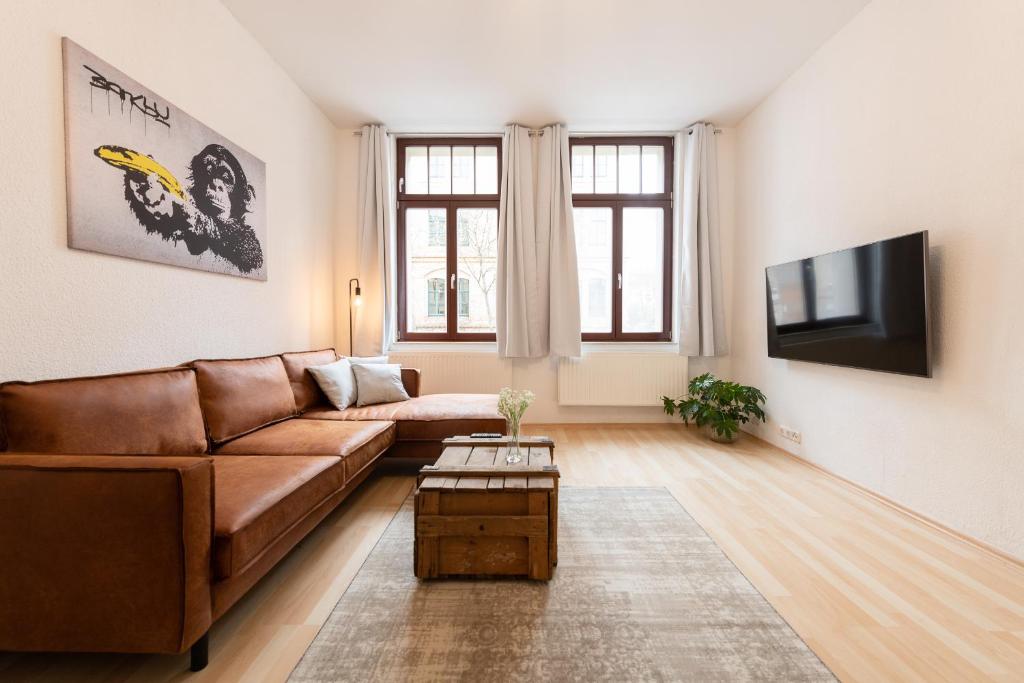 ein Wohnzimmer mit einem braunen Sofa und einem Flachbild-TV in der Unterkunft Ko-Living - Apartment am Wasserturm - vintage & industrial in Halle an der Saale