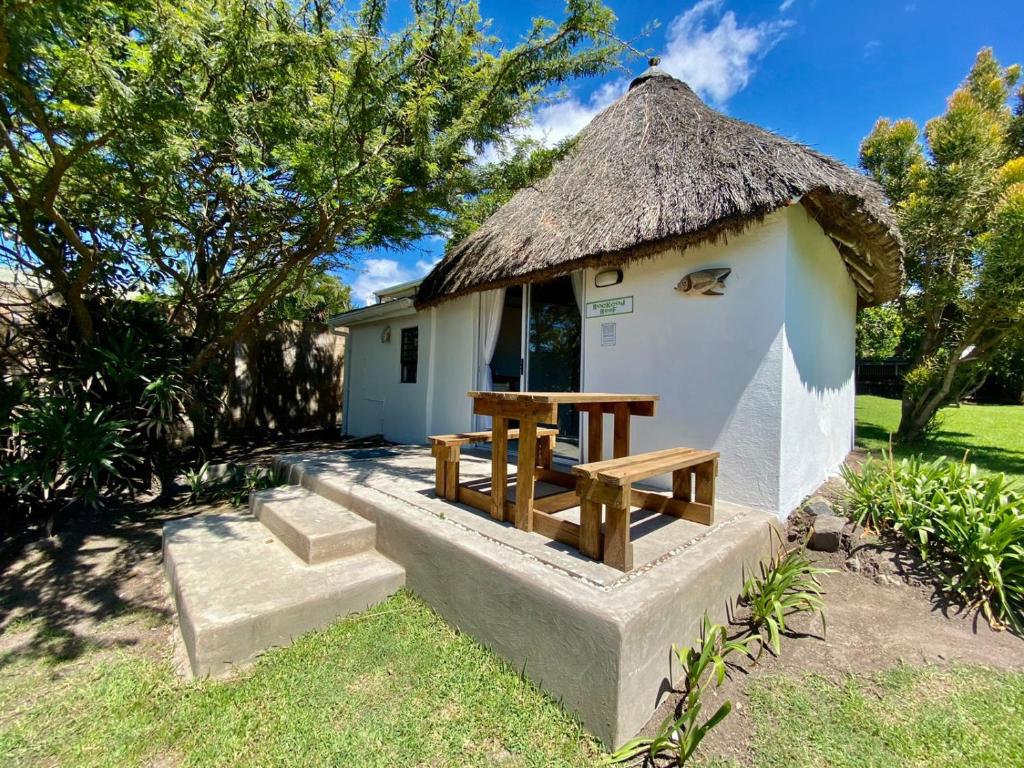 a small hut with a table and a thatched roof at Sunset Bed and Breakfast in Coffee Bay