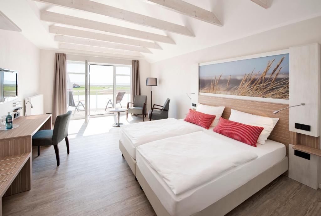 um quarto branco com uma grande cama branca e uma secretária em Hotel Strandhof em Baltrum