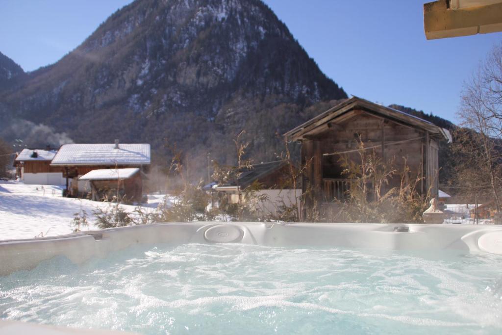 una bañera de hidromasaje en la nieve frente a una montaña en Gite Balnéo La Pomme de Pin en Sixt