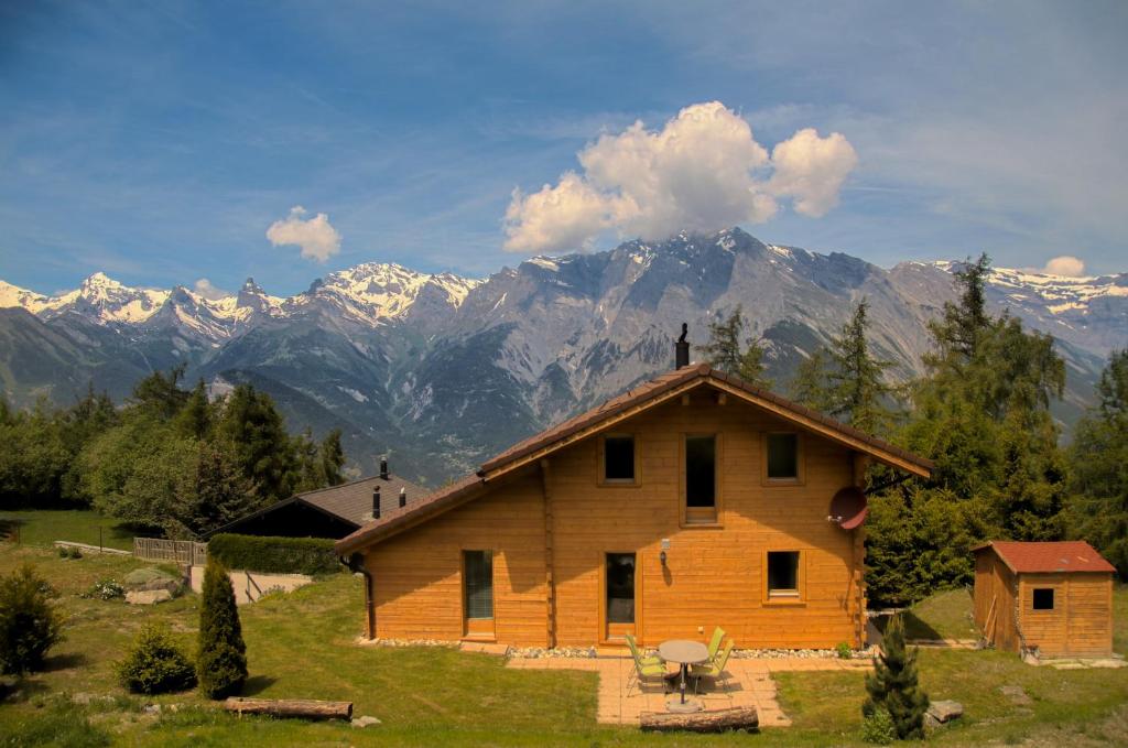 ein Holzhaus mit Bergen im Hintergrund in der Unterkunft Chalet Mon Sousou in Nendaz