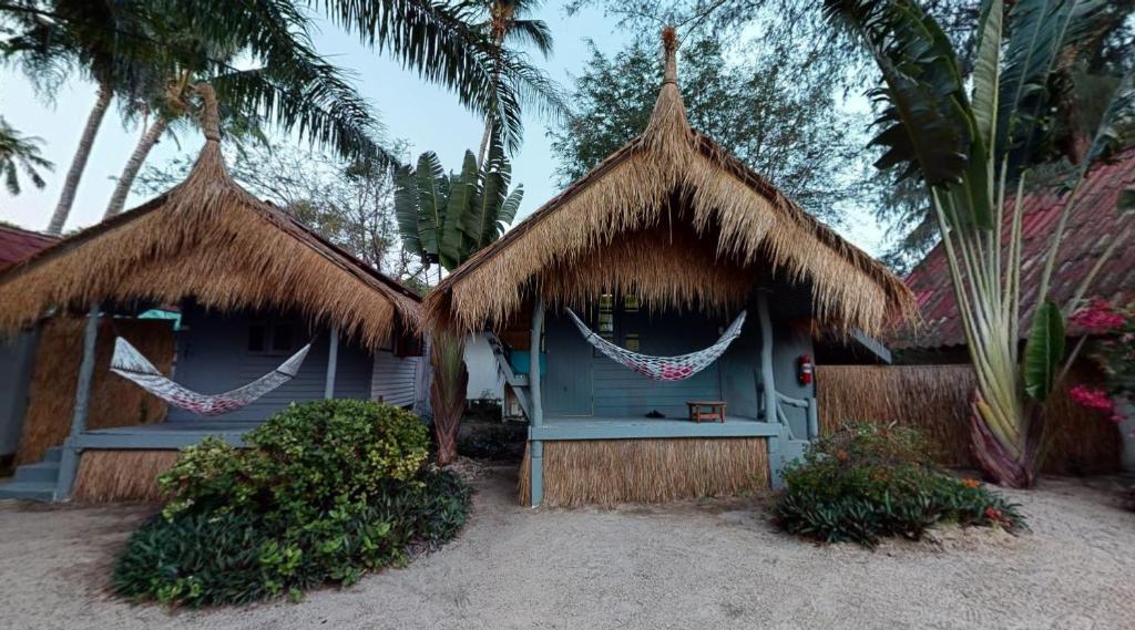 a blue house with straw huts and palm trees at Sea Love Beach Bar & Bungalows in Ban Tai