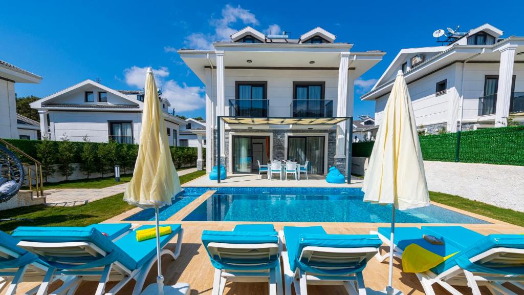 una casa con piscina con sedie e ombrelloni di Hisar 3 - Holiday Villa in Hisaronu a Fethiye