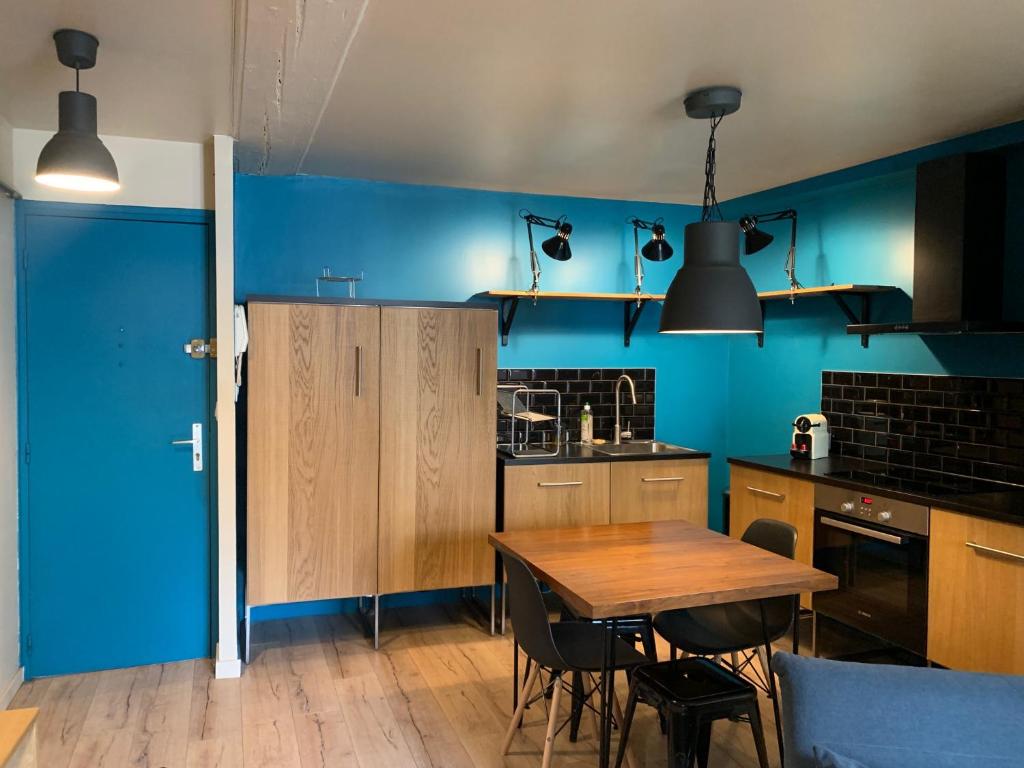 a kitchen with a wooden table and blue walls at Les Cloutiers in Chalon-sur-Saône