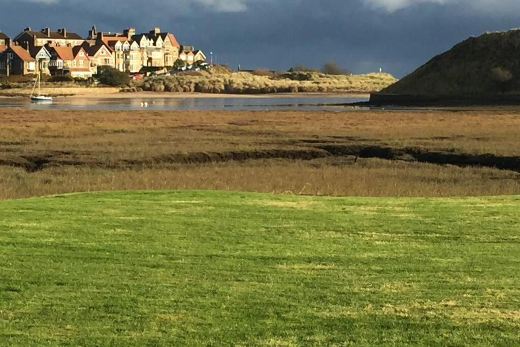 a field of green grass with houses in the background at Waterside view in Alnmouth