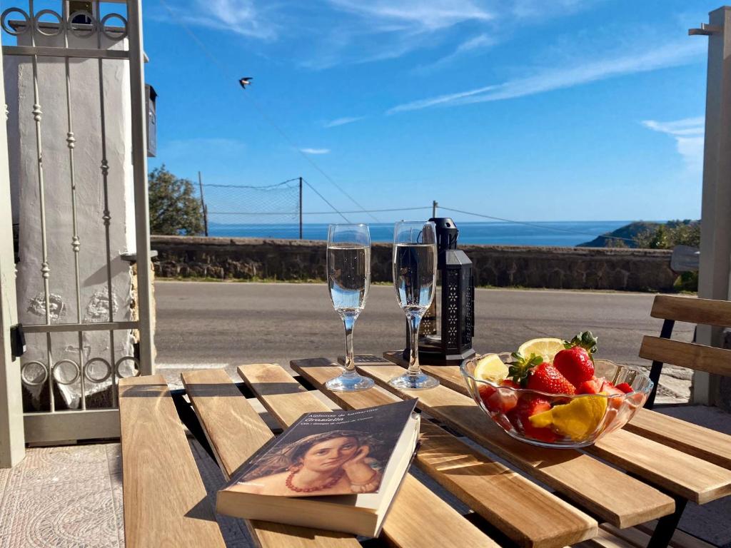 a wooden table with a bowl of fruit and wine glasses at Il Riccio Apartment in Procida