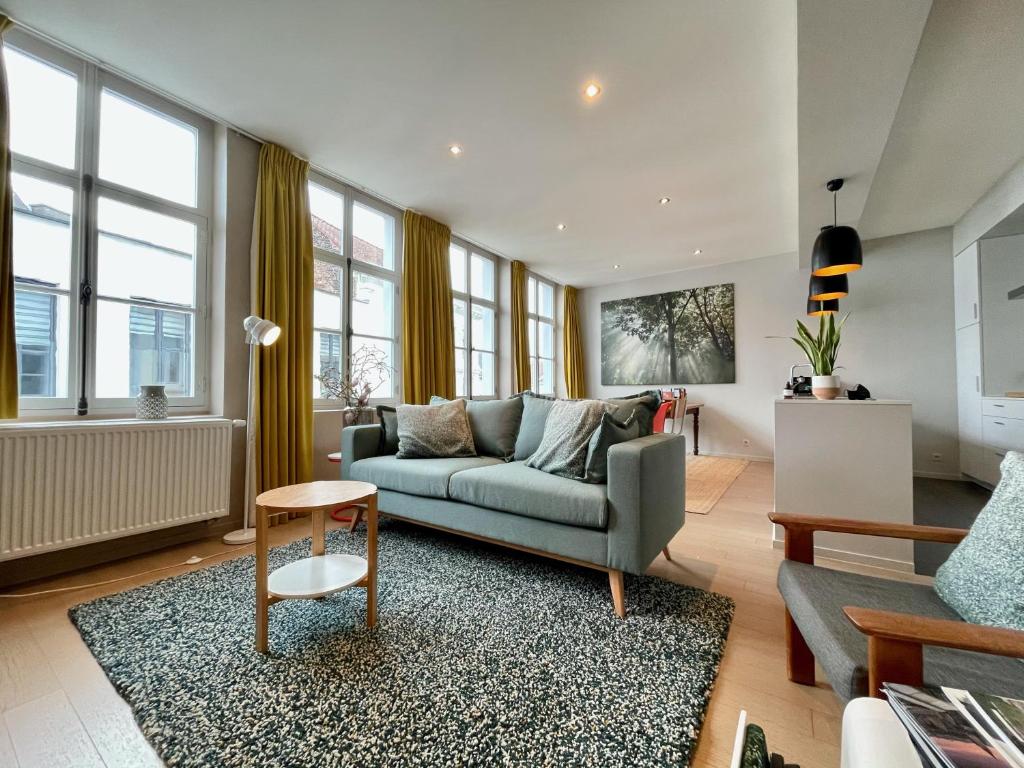ein Wohnzimmer mit einem Sofa und einigen Fenstern in der Unterkunft For Four Flat in Gent