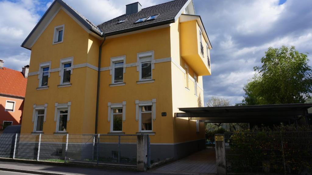 una casa amarilla con techo negro en Haus Piber, en Villach